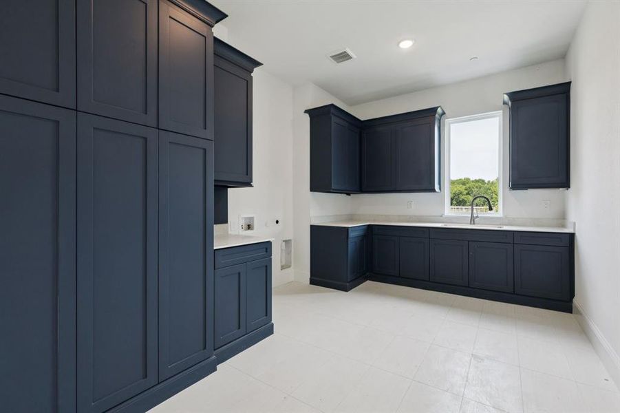 Oversized laundry room with sink and tons of cabinety and closet space.