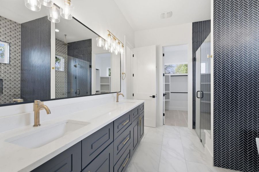Full bath featuring a spacious closet, double vanity, and a shower stall