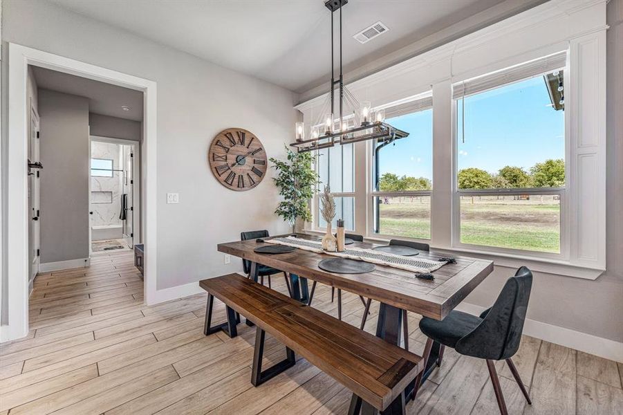 Dining space with light wood-style floors, plenty of natural light, and a chandelier