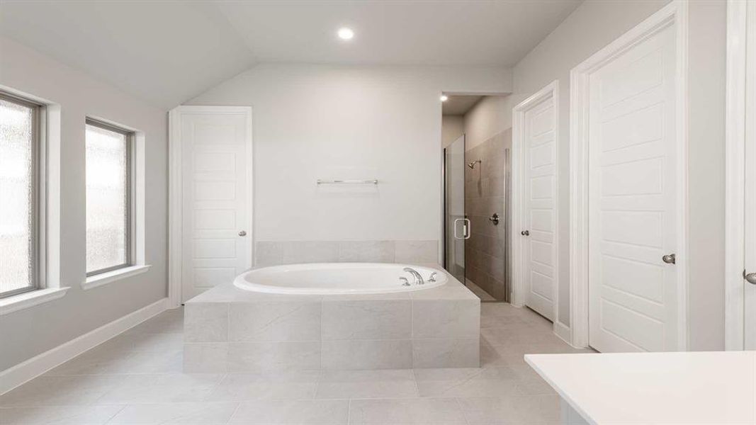 Bathroom with vaulted ceiling, tile patterned floors, and a healthy amount of sunlight