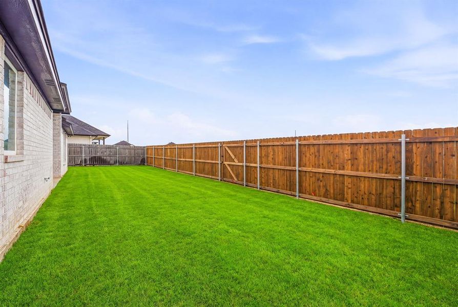 Expansive backyard featuring a well-maintained lawn and a tall wooden privacy fence