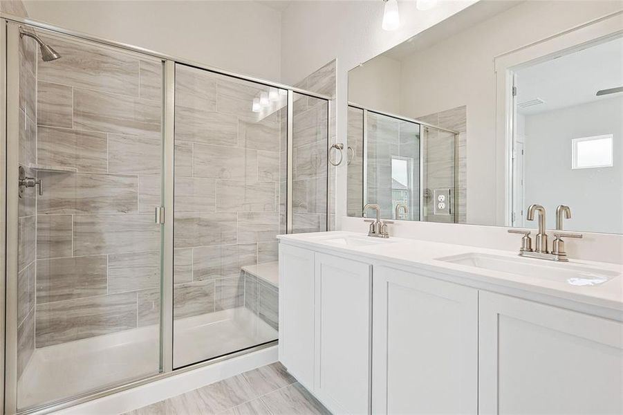 Bathroom with tile patterned floors, an enclosed shower, and dual bowl vanity