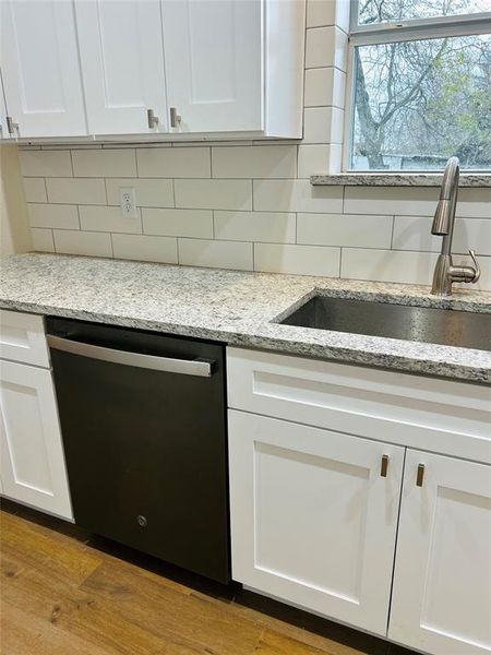 Kitchen featuring white cabinetry, dishwasher, light hardwood / wood-style floors, and sink