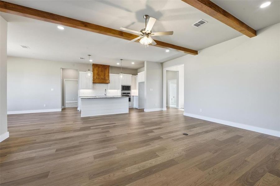 Unfurnished living room featuring recessed lighting, dark wood finished floors, a ceiling fan, and beamed ceiling