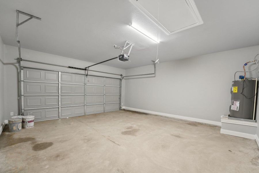 Garage featuring a garage door opener, water heater, and baseboards