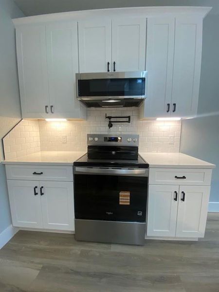 Bright white cabinetry and subway tile backsplash elevate this modern kitchen space. Bright white cabinetry and subway tile backsplash elevate this modern kitchen space.