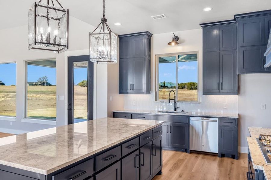 Kitchen with dishwasher, sink, hanging light fixtures, light hardwood / wood-style floors, and a kitchen island