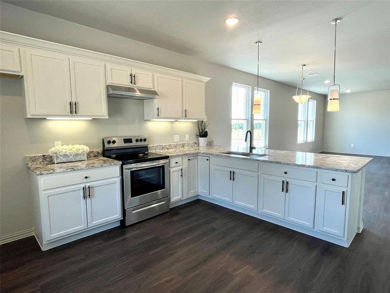 Kitchen featuring stainless steel range with electric stovetop, sink, decorative light fixtures, and white cabinets