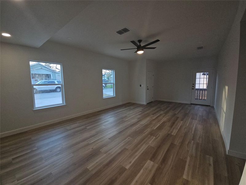 Unfurnished room with ceiling fan, visible vents, baseboards, and dark wood finished floors