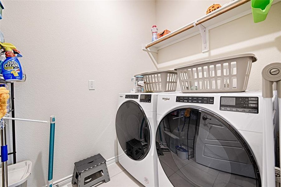 Laundry area with washer and dryer and light tile patterned floors