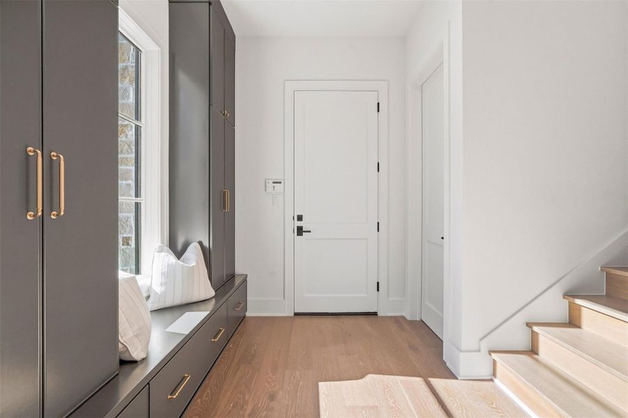 In the north wing of the home, a private stairway leads to a spacious bedroom (garage apartment), complete with a luxurious en-suite bath. This entrance from the garage also features an exceptional mudroom with bespoke cabinetry, integrated seating, and tailored storage solutions. Closed door to the right is your under-stairs storage. In the north wing of the home, a private stairway leads to a spacious bedroom (garage apartment), complete with a luxurious en-suite bath. This entrance from the garage also features an exceptional mudroom with bespoke cabinetry, integrated seating, and tailored storage solutions. Closed door to the right is your under-stairs storage.