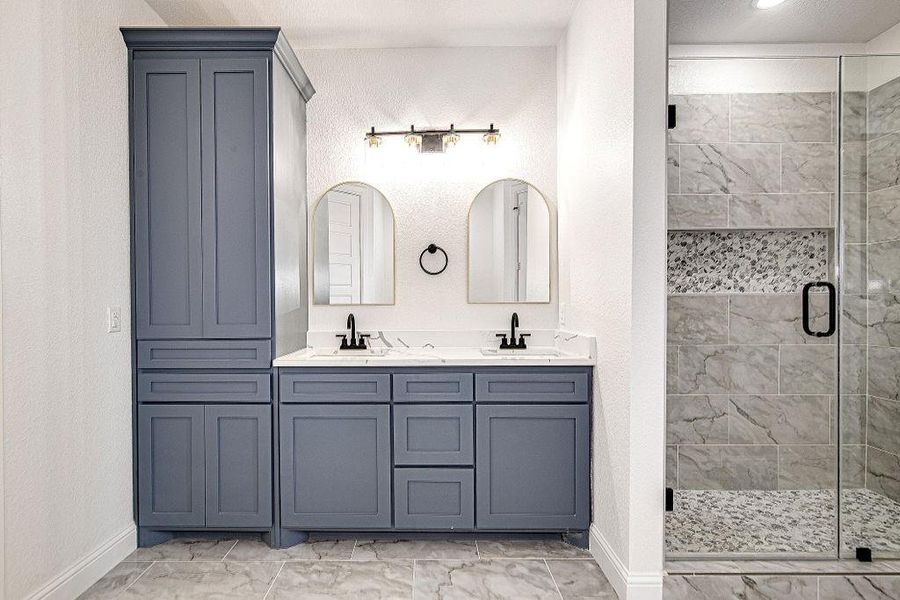 Bathroom featuring a sink, marble finish floor, and a stall shower