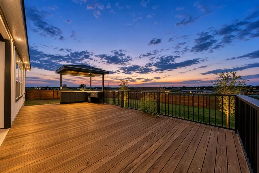 An expansive elevated wooden deck features a sheltered outdoor kitchen overlooking a fenced yard. An expansive elevated wooden deck features a sheltered outdoor kitchen overlooking a fenced yard.