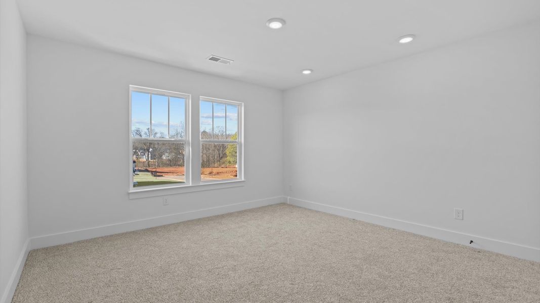 Highly functional bedroom with large windows, carpeted flooring, and tasteful finishes throughout