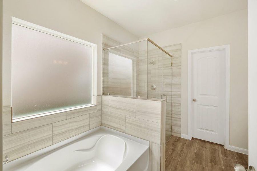 Enjoy spa-like luxury in this beautifully designed primary bathroom. Featuring a soaking tub, walk-in shower with modern tile surround, and frosted privacy window, this serene space is perfect for relaxation. High-end finishes make every detail shine.