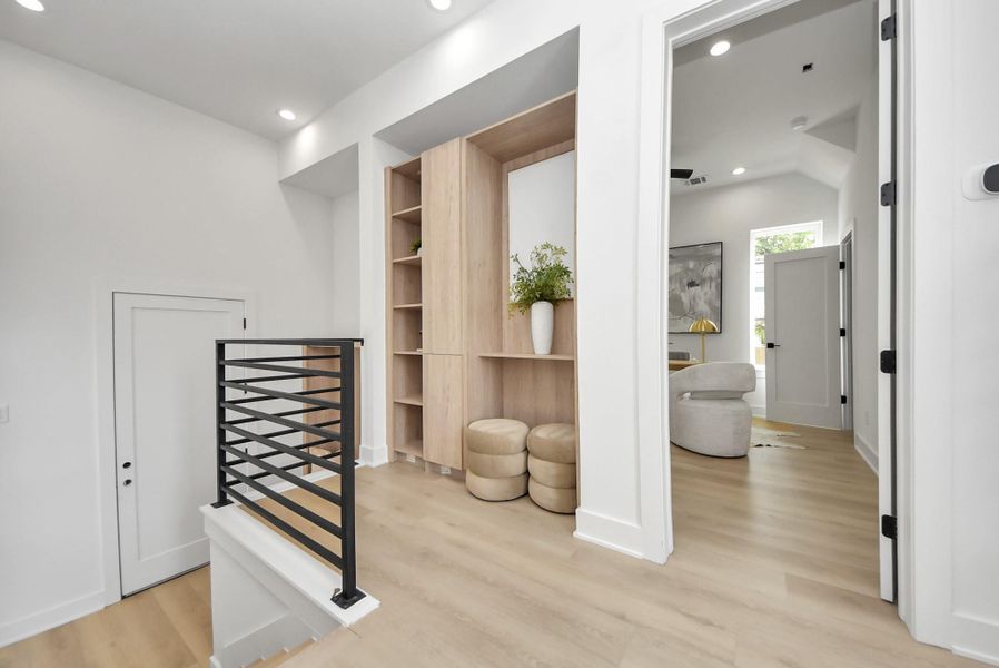 Upper landing showcasing light wood flooring, built-in storage, and access to the adjacent office.