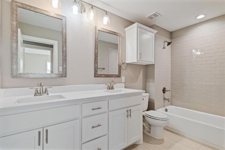 Full bathroom with tile patterned flooring, tiled shower / bath combo, toilet, and vanity