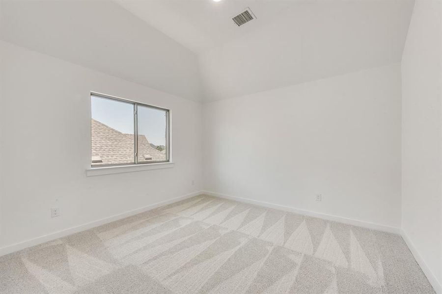 Carpeted spare room with vaulted ceiling and baseboards Carpeted spare room with vaulted ceiling and baseboards