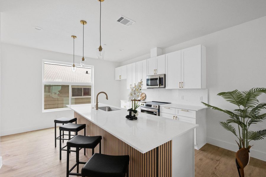 Modern kitchen featuring a large island with a quartz countertop, integrated sink, and bronze faucet
