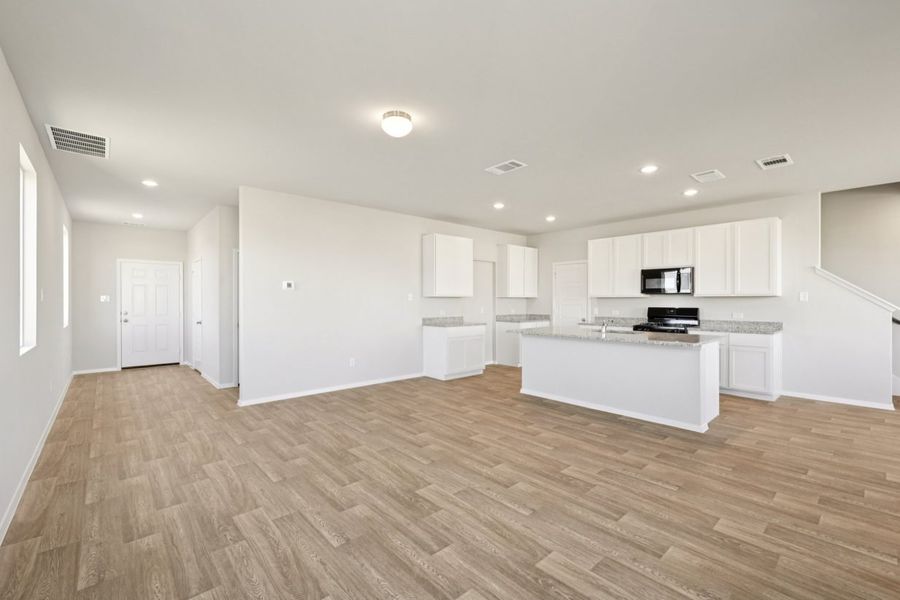 Image of a kitchen and living area with grey walls, vinyl flooring and a kitchen with white cabinets