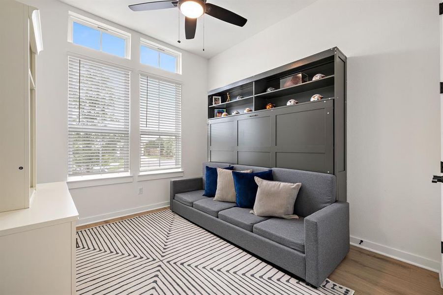 Well-lit room featuring high ceilings, a built-in wall unit, and durable wood flooring. Well-lit room featuring high ceilings, a built-in wall unit, and durable wood flooring.