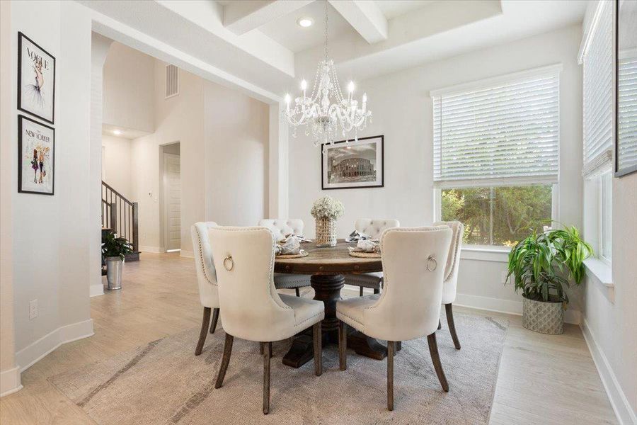 Dining room featuring a chandelier, light wood finished floors, and beamed ceiling