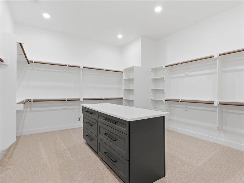 Spacious walk-in closet featuring an expansive central island with dark cabinetry and a light-toned countertop