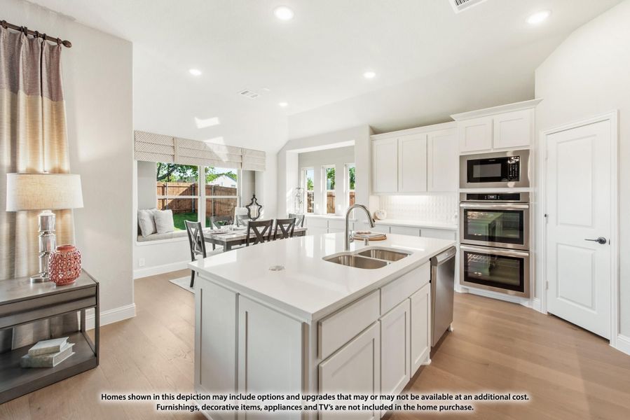 Open kitchen with white cabinets, center island with sink, stainless steel appliances, and view into dining area