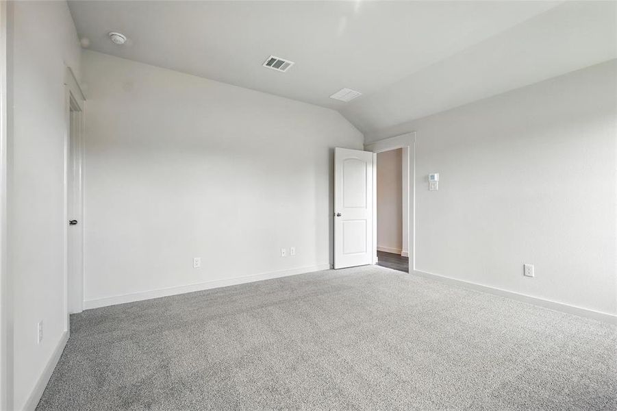 Empty room with carpet flooring, vaulted ceiling, and a smoke detector Empty room with carpet flooring, vaulted ceiling, and a smoke detector