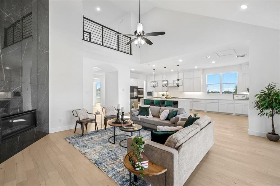 Living room with a premium fireplace, light wood finished floors, recessed lighting, high vaulted ceiling, and ceiling fan Living room with a premium fireplace, light wood finished floors, recessed lighting, high vaulted ceiling, and ceiling fan