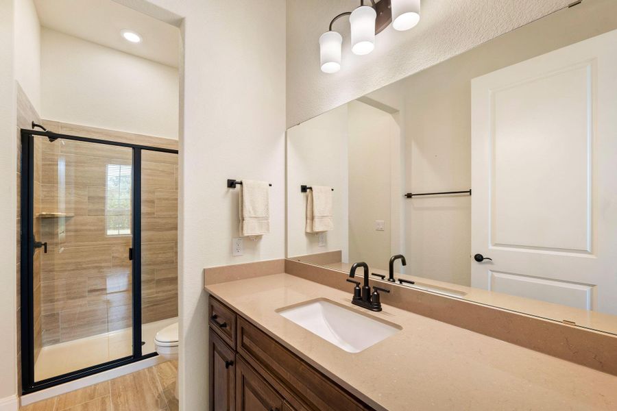 A well-appointed bathroom features a single vanity, a spacious mirror, and a convenient walk-in shower. A well-appointed bathroom features a single vanity, a spacious mirror, and a convenient walk-in shower.