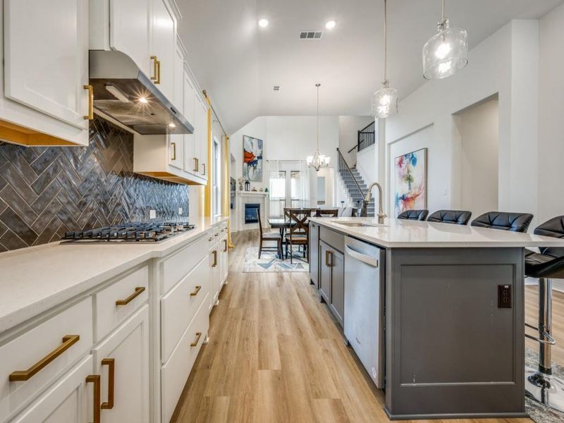 Kitchen featuring light countertops, ventilation hood, a sink, appliances with stainless steel finishes, and light wood-style floors