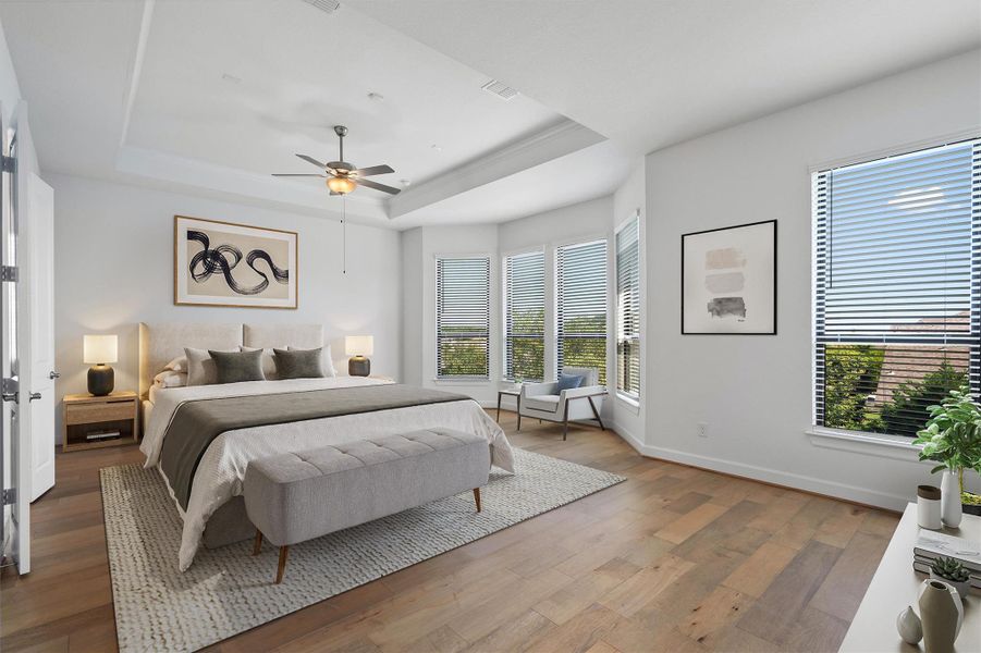 Spacious room featuring wood-finish flooring, a tray ceiling with a ceiling fan, and multiple windows with blinds