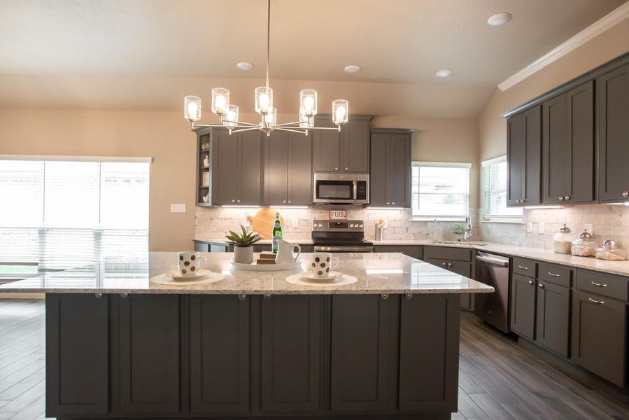 Kitchen with appliances with stainless steel finishes, a center island, decorative backsplash, light stone counters, and dark wood-style flooring Kitchen with appliances with stainless steel finishes, a center island, decorative backsplash, light stone counters, and dark wood-style flooring