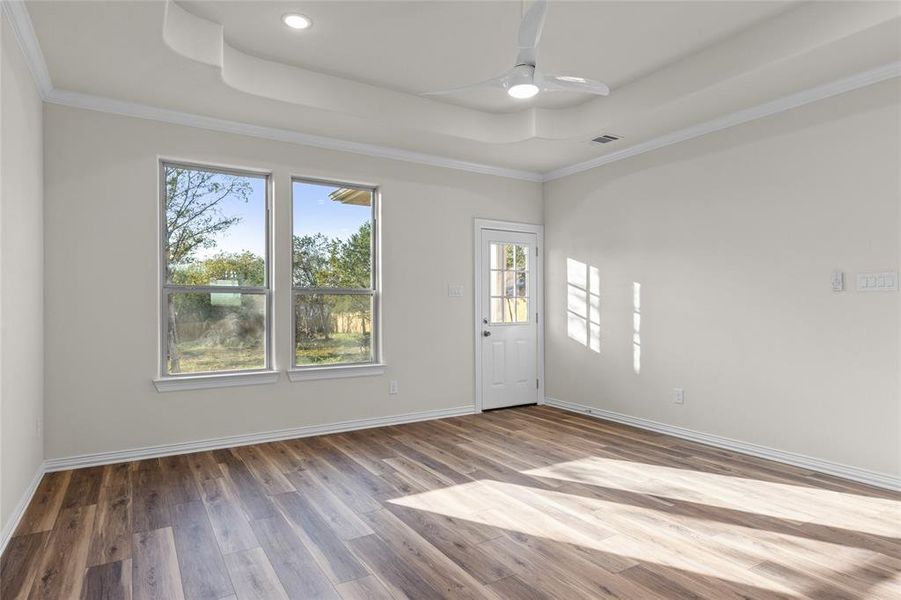 Unfurnished room featuring a raised ceiling, wood finished floors, a ceiling fan, crown molding, and recessed lighting