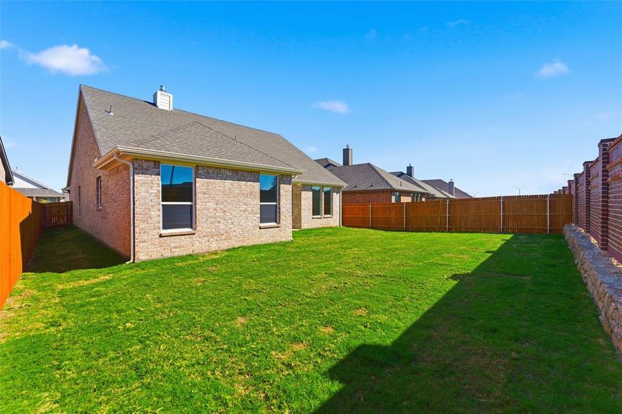 Back of house with a fenced backyard, a chimney, brick siding, and a shingled roof