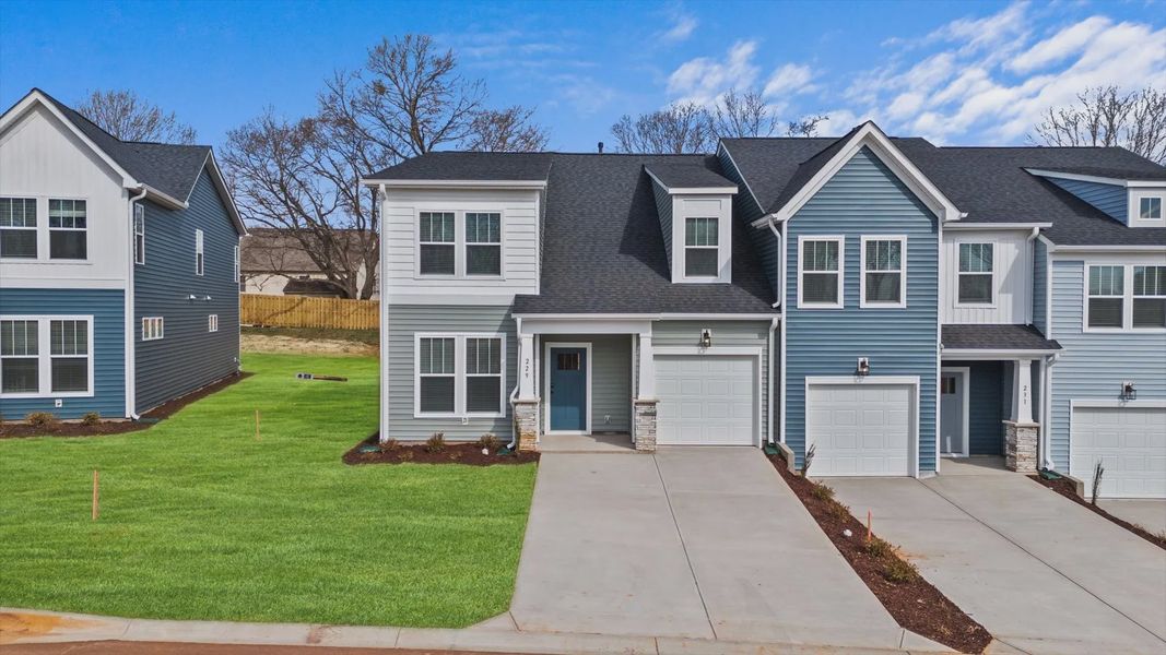 Townhome exterior with blue and white vinyl, stone columns, garage, and two car parking pad at Aspen Ridge by DRB Homes Townhome exterior with blue and white vinyl, stone columns, garage, and two car parking pad at Aspen Ridge by DRB Homes