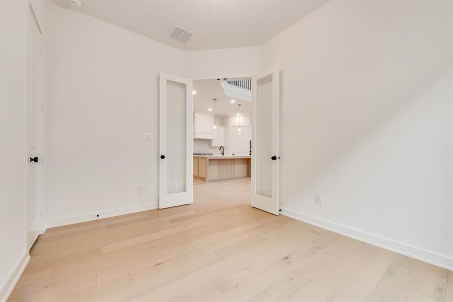 Unfurnished room featuring light wood-style floors, recessed lighting, and french doors Unfurnished room featuring light wood-style floors, recessed lighting, and french doors