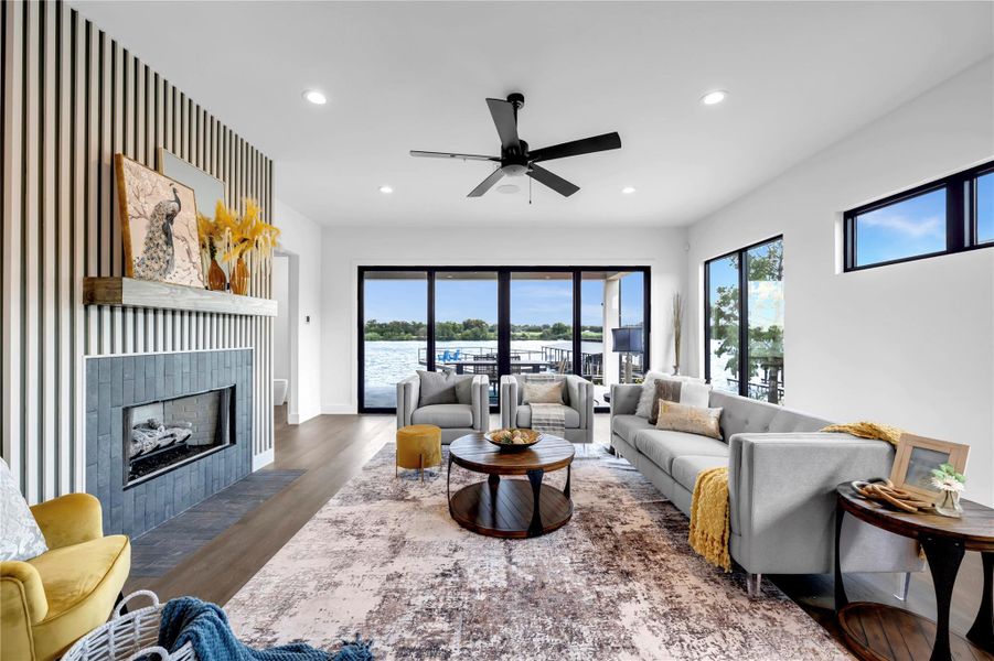 Living area with wood finished floors, a fireplace, recessed lighting, ceiling fan, and a water view