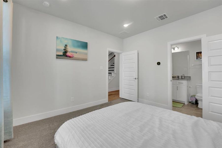 Carpeted bedroom featuring connected bathroom