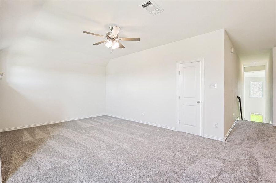 Carpeted spare room featuring lofted ceiling and ceiling fan