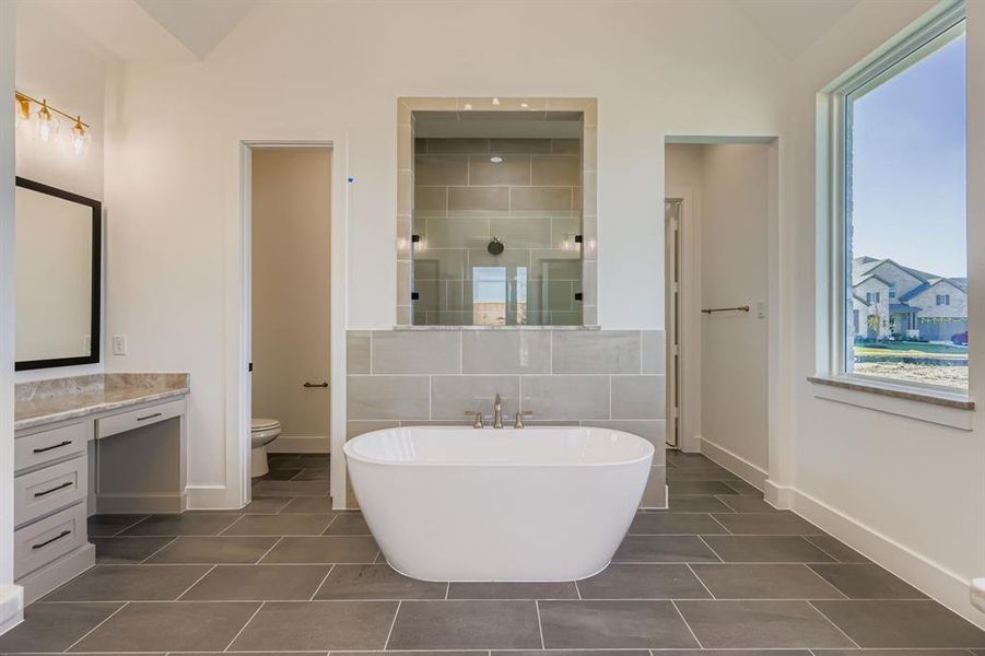 Full bathroom with a freestanding tub, a shower stall, dark tile patterned flooring, tile walls, and vanity