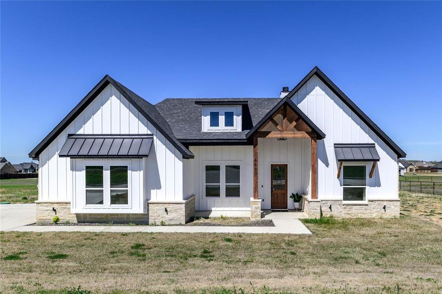 Modern inspired farmhouse featuring a standing seam roof, a shingled roof, board and batten siding, and a metal roof Modern inspired farmhouse featuring a standing seam roof, a shingled roof, board and batten siding, and a metal roof