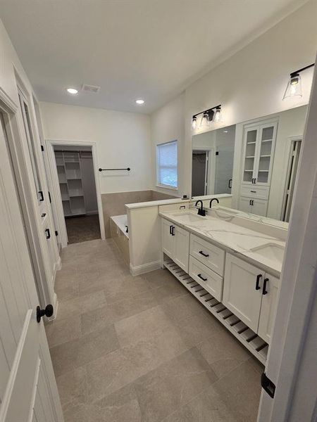 Bathroom with tile patterned flooring, a bathtub, and dual bowl vanity