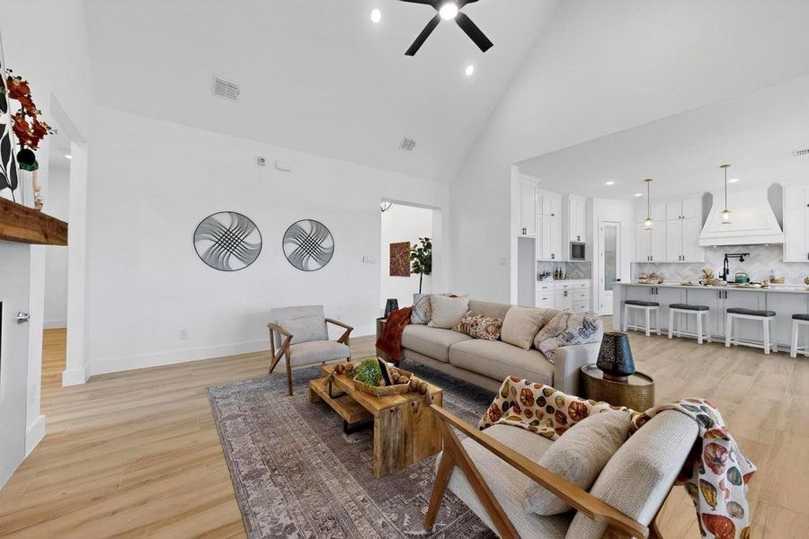 Living area featuring high vaulted ceiling, light wood-style floors, recessed lighting, and a ceiling fan Living area featuring high vaulted ceiling, light wood-style floors, recessed lighting, and a ceiling fan