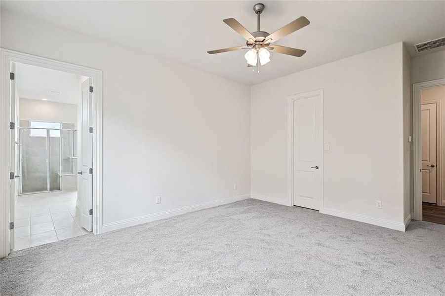 Unfurnished bedroom with light carpet, connected bathroom, and ceiling fan