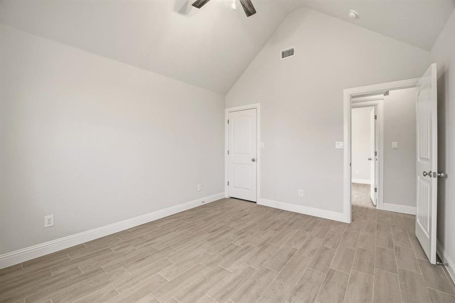 Unfurnished bedroom featuring a high ceiling, a ceiling fan, and wood tiled floors