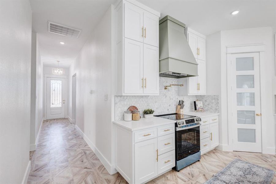 Kitchen featuring electric range, backsplash, premium range hood, and light parquet flooring