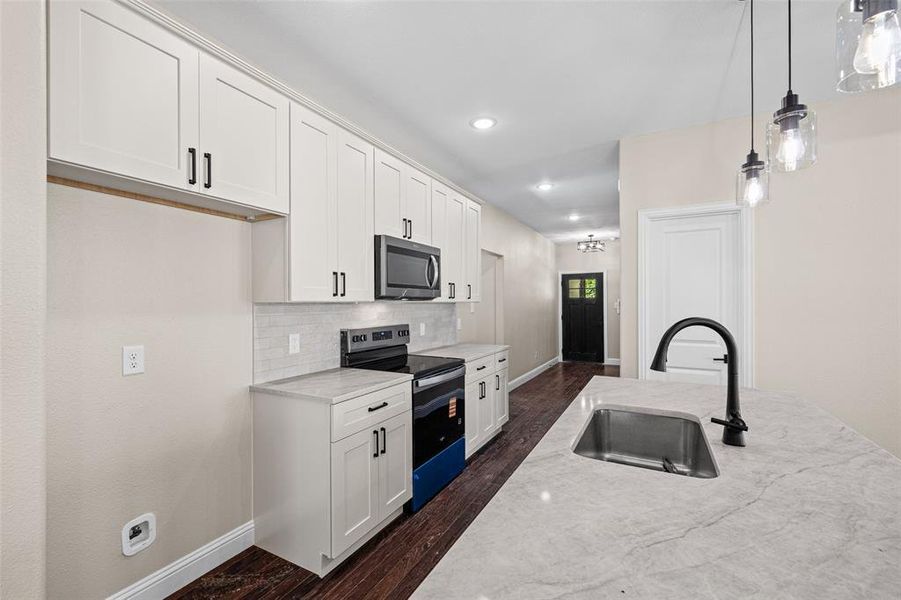 Modern kitchen featuring white shaker cabinetry with dark hardware