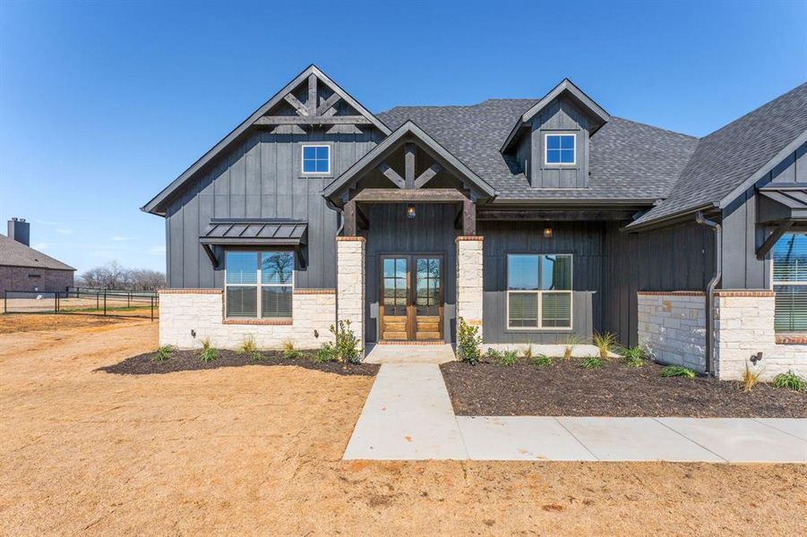 View of front of property featuring a shingled roof, french doors, stone siding, and board and batten siding